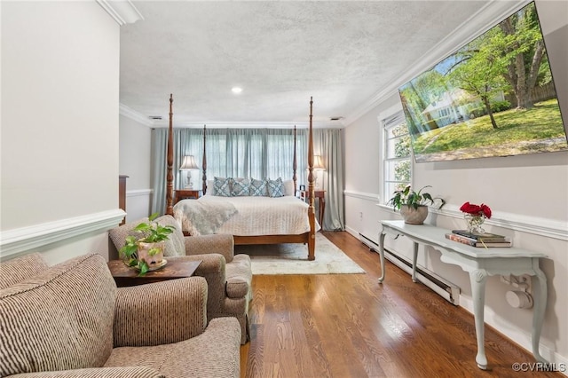 bedroom with crown molding, baseboard heating, and wood finished floors