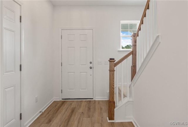 foyer entrance with stairs, baseboards, and light wood-type flooring