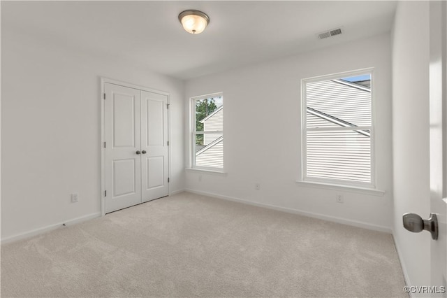 unfurnished bedroom with carpet floors, baseboards, visible vents, and a closet