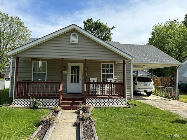 bungalow-style house with a shingled roof, a front lawn, an attached carport, covered porch, and driveway