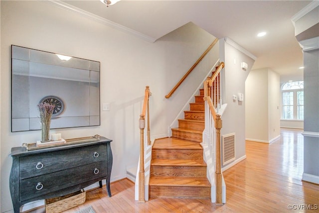 stairway featuring wood finished floors, baseboards, and ornamental molding