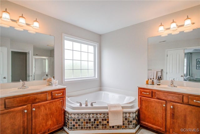 bathroom with a stall shower, a garden tub, and two vanities