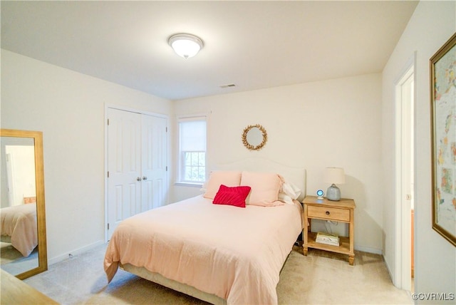 bedroom with light colored carpet, a closet, and baseboards