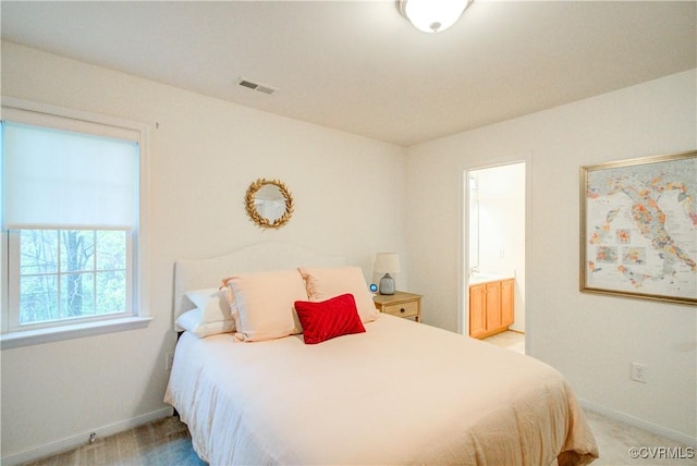 bedroom with light carpet, baseboards, and ensuite bath