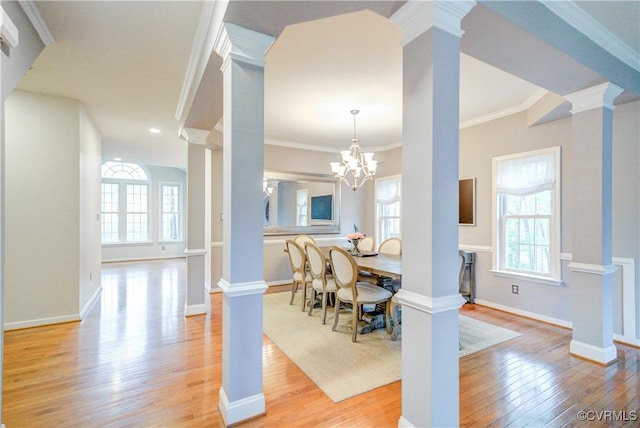 dining area with decorative columns, light wood-type flooring, ornamental molding, baseboards, and a chandelier