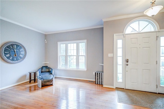 entrance foyer featuring wood finished floors, healthy amount of natural light, crown molding, and baseboards