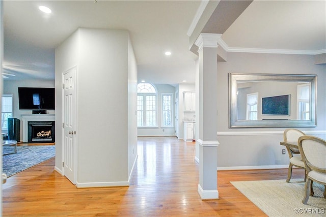 hallway with ornate columns, light wood finished floors, crown molding, baseboards, and recessed lighting