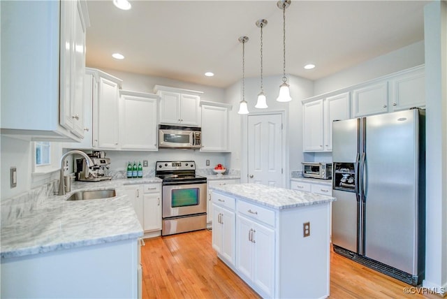 kitchen featuring appliances with stainless steel finishes, a sink, a center island, white cabinetry, and pendant lighting