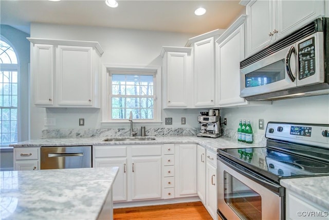 kitchen with stainless steel appliances, a sink, white cabinets, recessed lighting, and light wood-type flooring