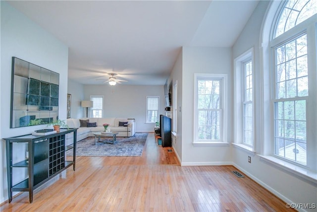 living area with wood-type flooring, baseboards, and ceiling fan