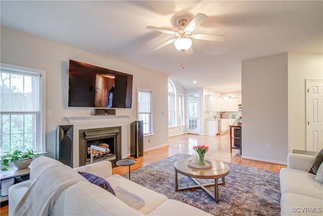 living room with ceiling fan, light wood-style floors, a fireplace, baseboards, and recessed lighting