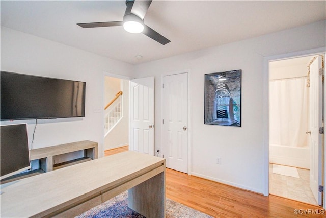 unfurnished office with light wood-style floors, a ceiling fan, and baseboards