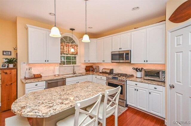 kitchen featuring a toaster, a kitchen breakfast bar, white cabinets, a sink, and appliances with stainless steel finishes