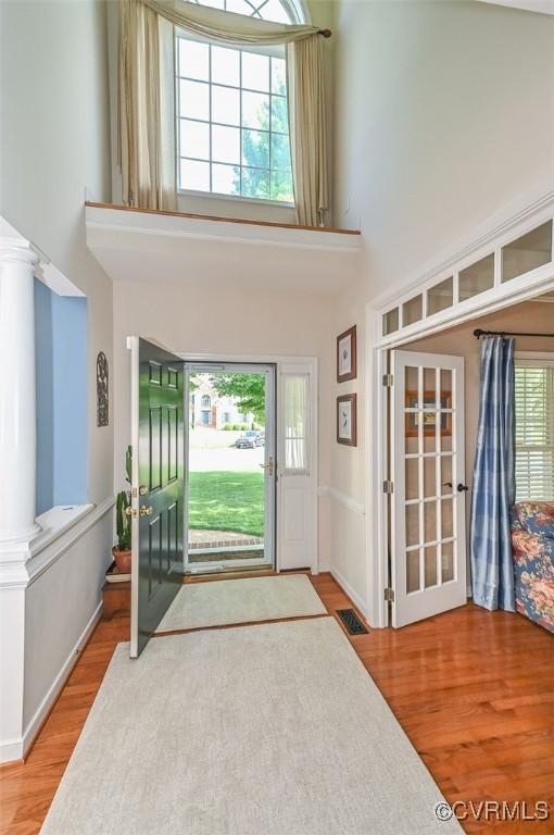 entryway featuring a high ceiling, visible vents, and wood finished floors