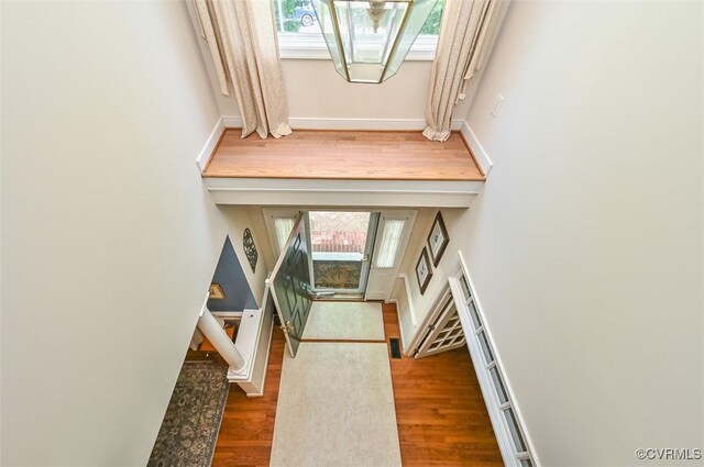 entryway with baseboards, wood finished floors, and a towering ceiling