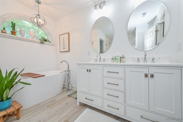 bathroom featuring double vanity, a sink, wood finished floors, and a soaking tub