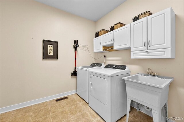 clothes washing area with visible vents, baseboards, washer and clothes dryer, a sink, and cabinet space