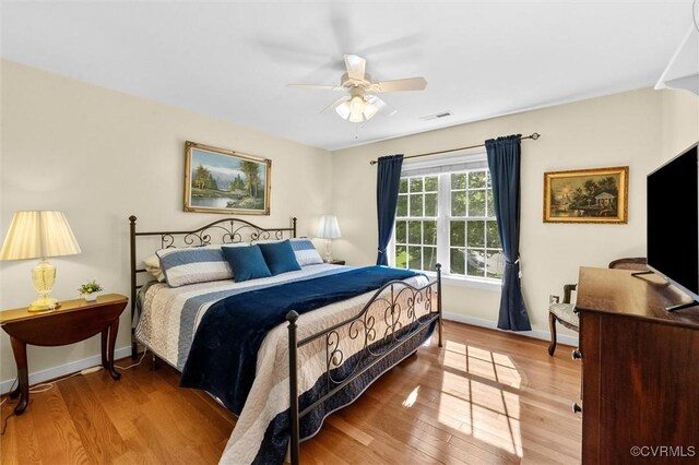 bedroom featuring baseboards, ceiling fan, wood finished floors, and visible vents