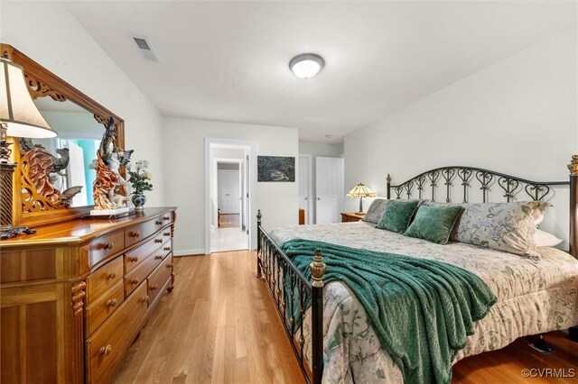 bedroom featuring visible vents, light wood-style flooring, and baseboards