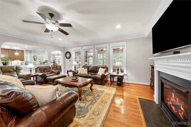 living area featuring light wood finished floors, arched walkways, a ceiling fan, recessed lighting, and a fireplace with flush hearth