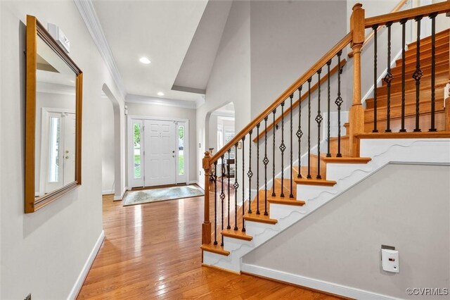 foyer featuring stairs, baseboards, ornamental molding, and hardwood / wood-style floors