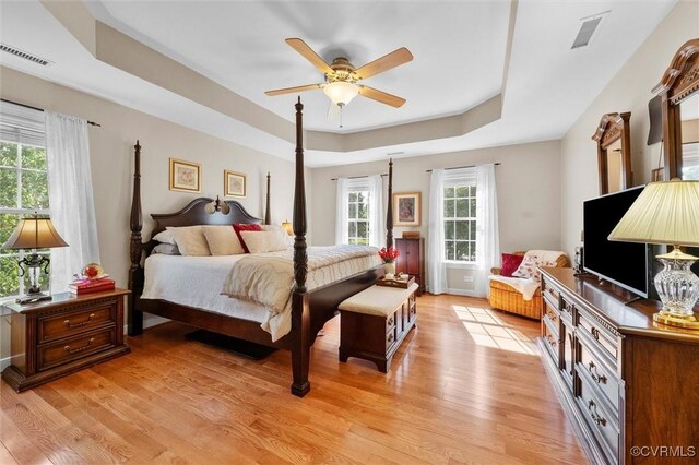bedroom with visible vents, a ceiling fan, a raised ceiling, and light wood-style floors