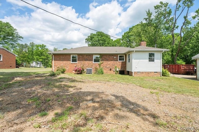 rear view of house with a chimney, central AC, a yard, and crawl space