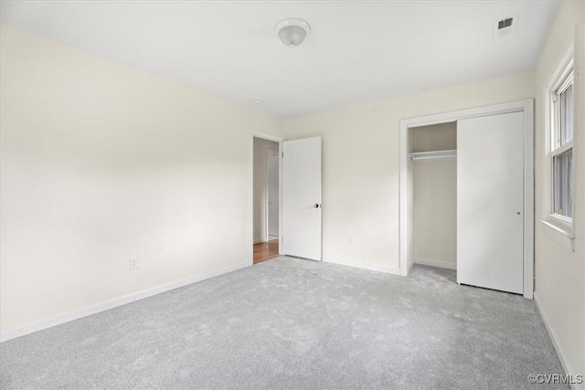 unfurnished bedroom with a closet, carpet, baseboards, and visible vents