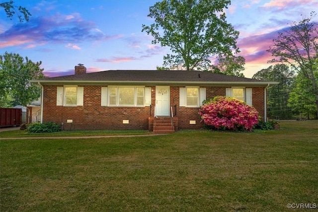 ranch-style home featuring entry steps, a chimney, a front lawn, and brick siding
