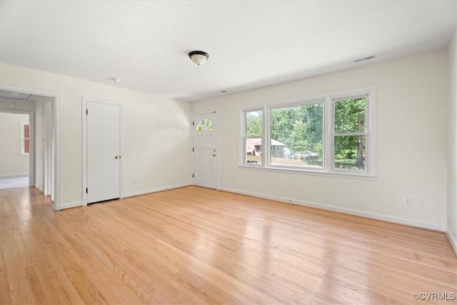spare room featuring visible vents, attic access, light wood-style floors, and baseboards