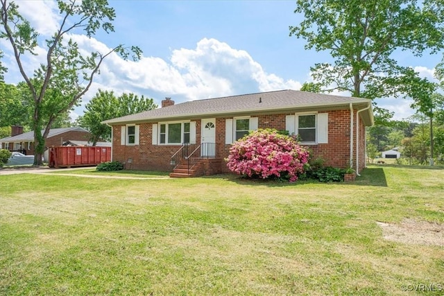 single story home with a chimney, a front yard, and brick siding