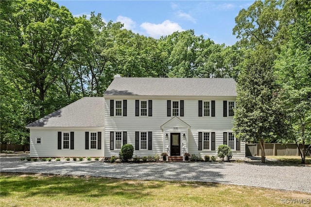 colonial-style house with roof with shingles and fence