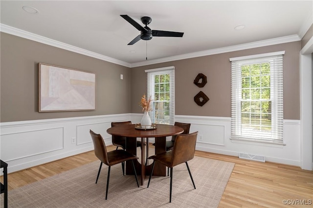 dining area featuring visible vents, a ceiling fan, light wood-style floors, and crown molding