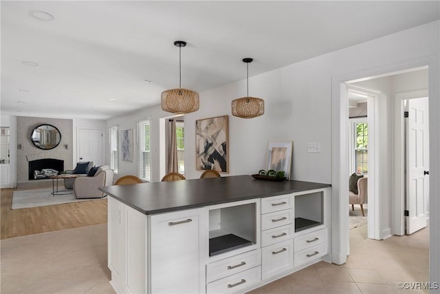 kitchen with white cabinetry, a fireplace, a healthy amount of sunlight, and dark countertops