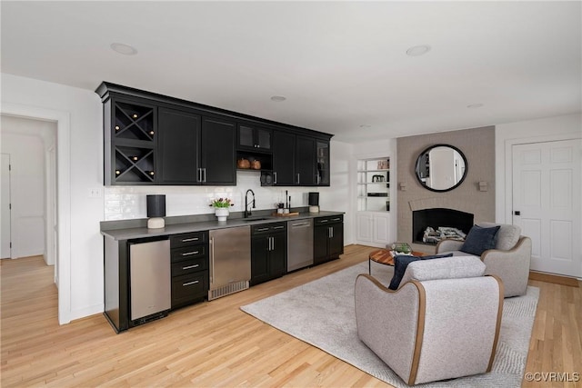 bar featuring fridge, a sink, wet bar, light wood-type flooring, and stainless steel dishwasher