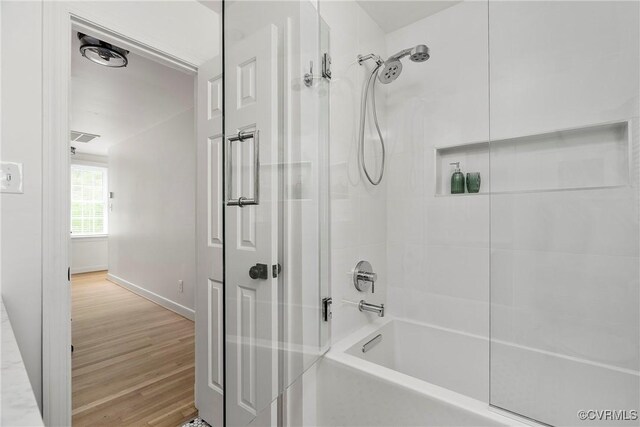 bathroom with baseboards, bathtub / shower combination, wood finished floors, and visible vents