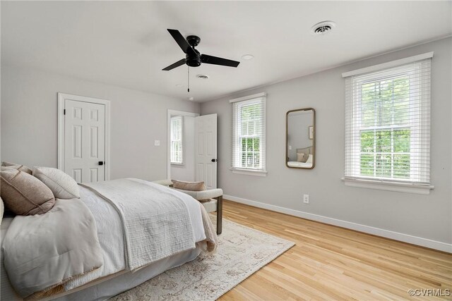 bedroom featuring baseboards, a ceiling fan, wood finished floors, and visible vents