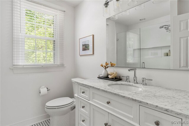 bathroom featuring toilet, baseboards, a healthy amount of sunlight, and vanity