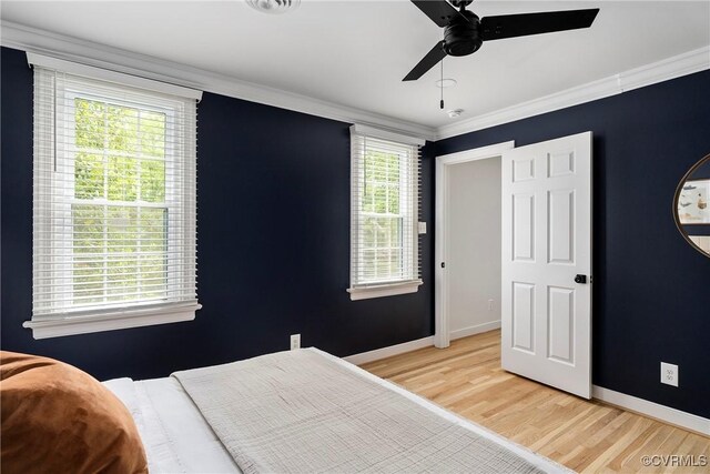 bedroom with crown molding, light wood-style flooring, ceiling fan, and baseboards