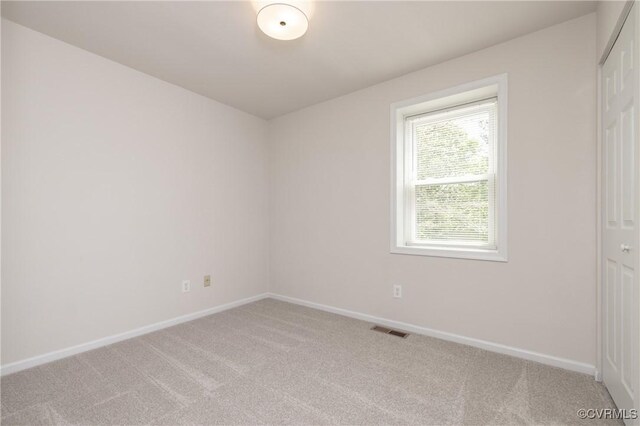 spare room featuring light colored carpet, baseboards, and visible vents