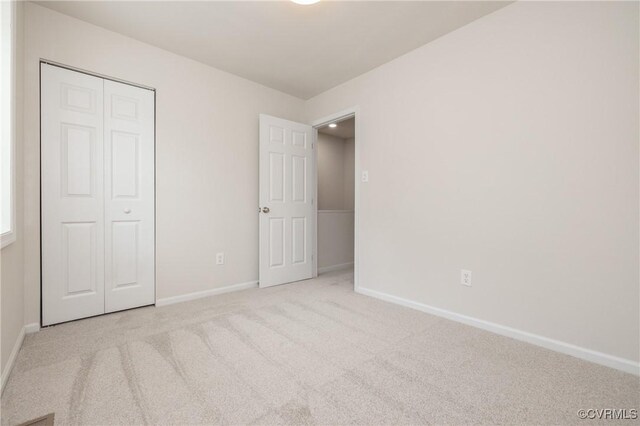 unfurnished bedroom with baseboards, carpet, and a closet