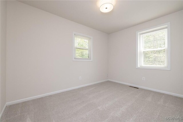 unfurnished room featuring baseboards, visible vents, and light carpet