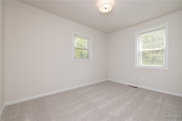 empty room featuring baseboards, light colored carpet, and visible vents