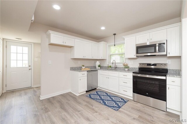 kitchen with light stone counters, light wood-type flooring, white cabinets, and stainless steel appliances