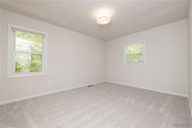 spare room with baseboards, visible vents, and light carpet