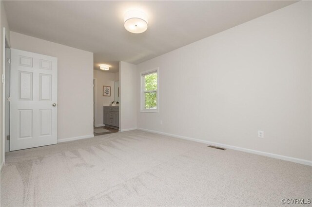 empty room with baseboards, visible vents, and light colored carpet