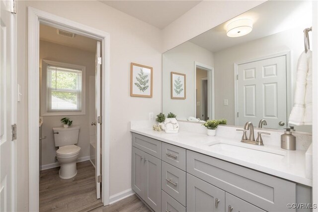 bathroom featuring vanity, visible vents, wood finished floors, toilet, and baseboards