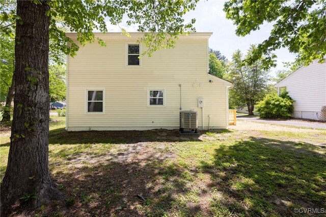 rear view of house featuring a lawn and central air condition unit
