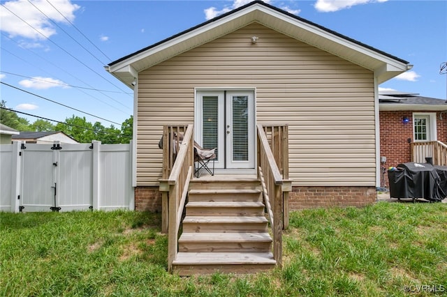 rear view of property featuring a lawn, a gate, fence, and french doors