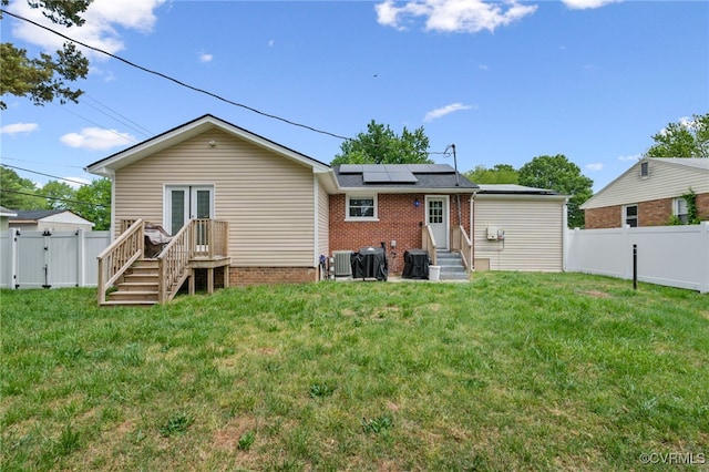 back of property with a gate, a fenced backyard, a yard, and solar panels